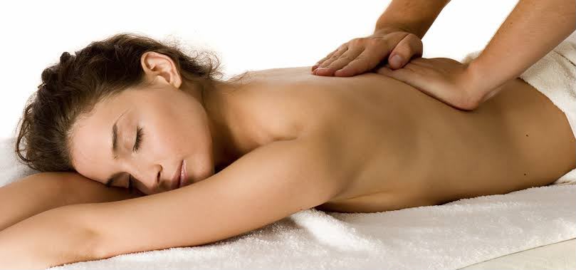 Massage oil being poured onto a relaxed back during a Swedish massage